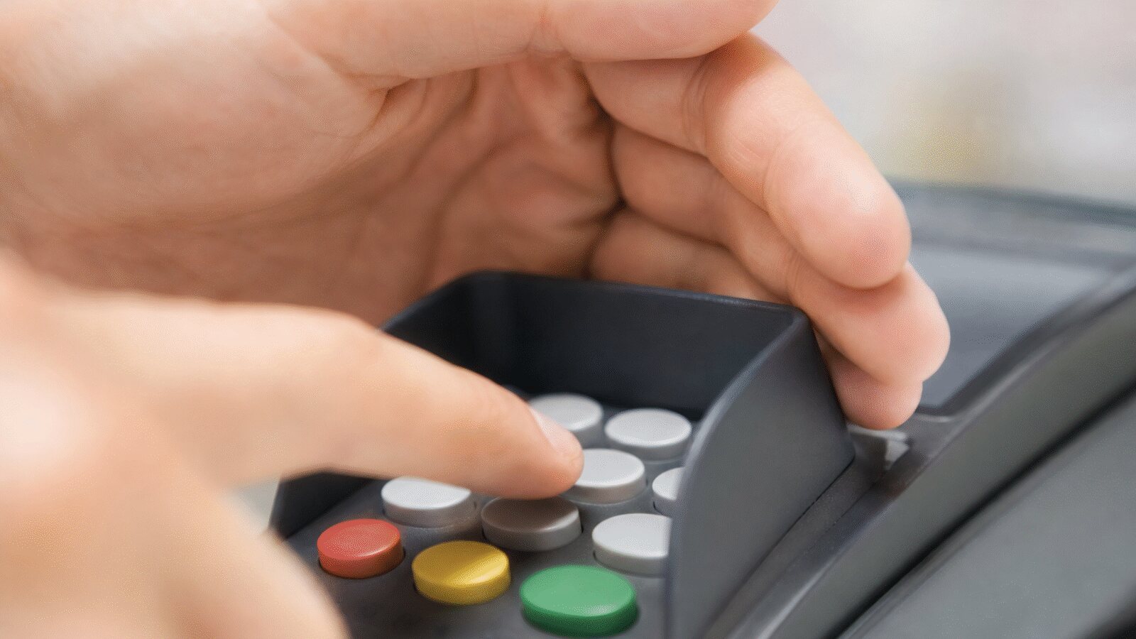 Kéz takarja el a fizetési terminál billentyűzetét PIN-kód beírása közben